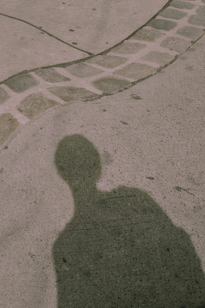 Das Foto zeigt einen Ausschnitt einer Straße, sowie den Schatten einer Person.