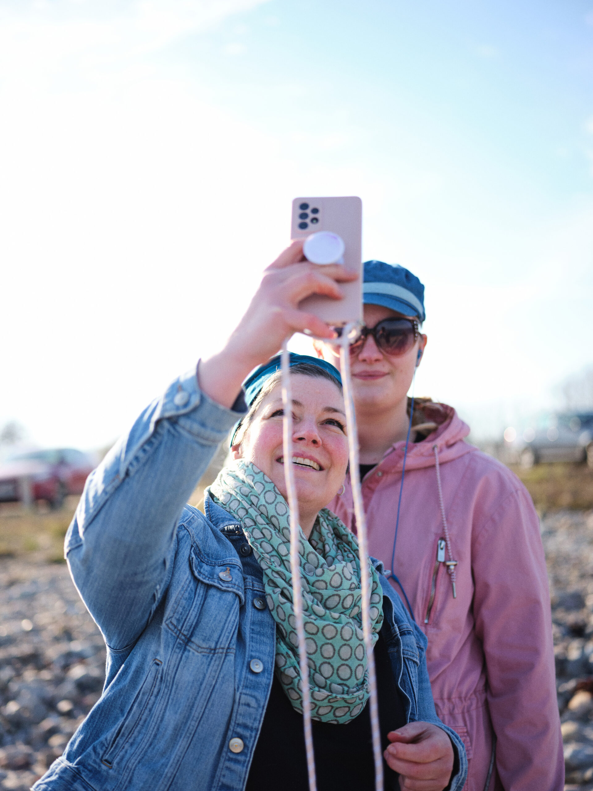 Frederike steht mit ihrer Tochter draußen. Sie machen ein Selfie mit dem Handy zusammen und lächeln.