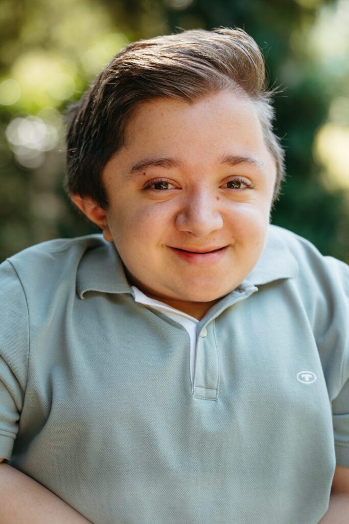 Ein junger Mann schaut mit freundlichen Blick in die Kamera. Er trägt kurze braune Haare und hat braune Augen.