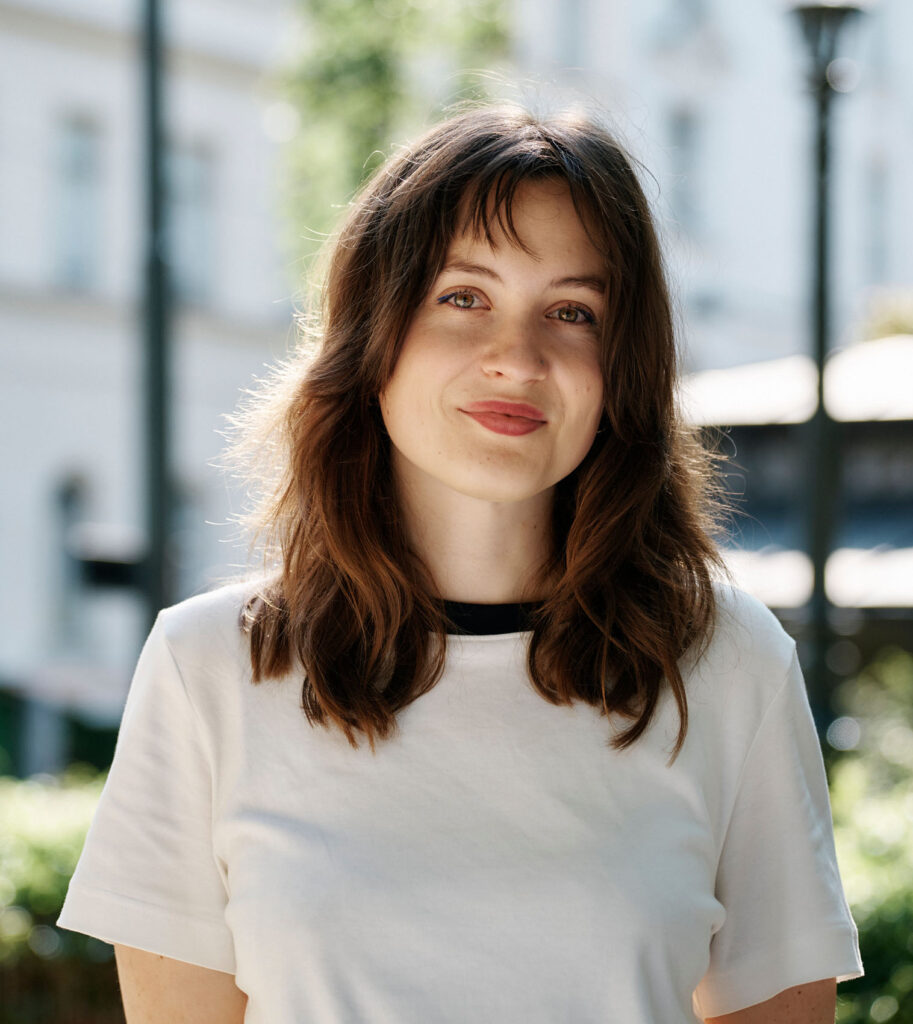Lisa-Marie hat braune schulterlange Haare. Sie trägt ein weißes T-Shirt und schaut mit freundlichen Blick in die Kamera.