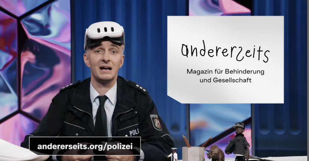 Das Bild zeigt Jan Böhmermann, einen bekannten Moderator, der hinter einem Tisch sitzt. Er trägt einen Polizeiuniform. Rechts neben ihm sieht man eine Grafik mit der Aufschrift „andererseits – Magazin für Behinderung und Gesellschaft“. Der Hintergrund ist bunt und modern gestaltet.