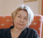 Eine Frau mit blonden kurzen Haaren, schaut mit ernsten Blick in die Kamera.