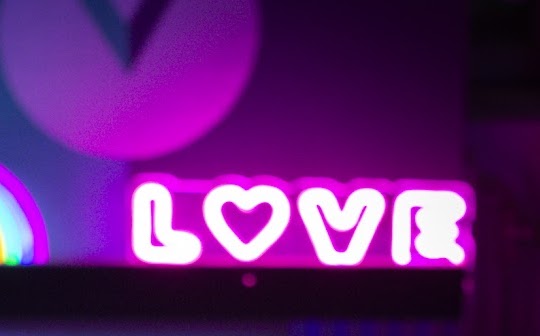 Das Bild zeigt das Wort "love" in pinker Leuchtschrift.