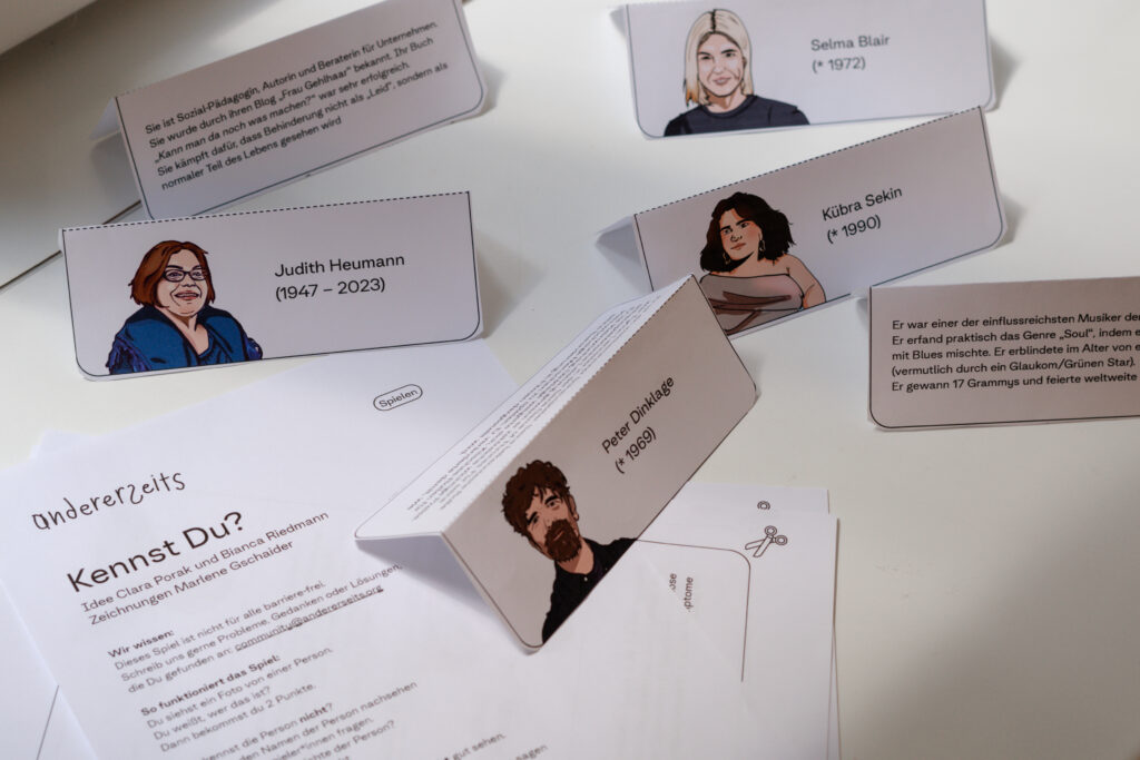 Aus Papier ausgeschnitte Kärtchen stehen auf weißem Untergrund. Auf den Kärtchen sind Zeichnungen von Personen und die Namen.